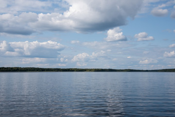 Summer view of the lake Hallanlahti with clouds on blue sky .