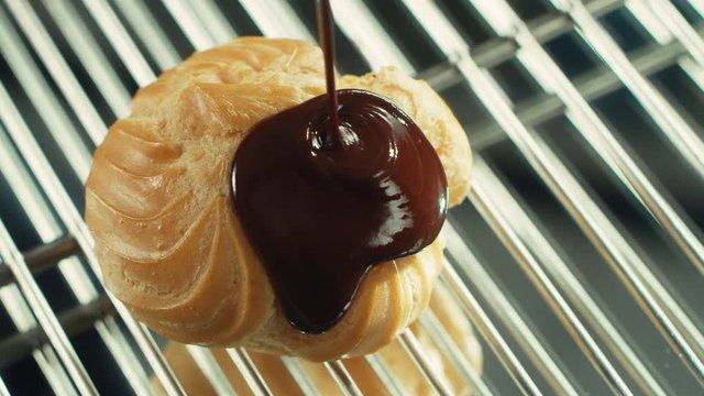 Closeup choux pastry pouring with chocolate at professional restaurant.