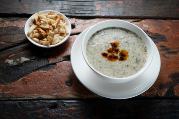Traditional Turkish yogurt soup with croutons aside isolated on rustic wooden table