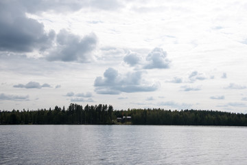 Summer view of the lake Hallanlahti with clouds on blue sky .