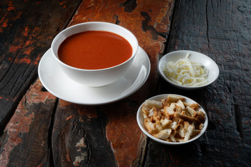 Traditional Turkish tomato soup with cheese and croutons aside isolated on wooden background