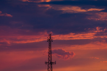 Cell Phone Tower Silhouetted Against Orange and Purple Clouds at Sunset