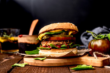 Wegański burger z kotletem z ciecierzycy, listkami szpinaku, pomidorem i sosem musztardowym. podany na papierze, na drewnianej desce.