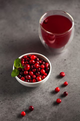 cranberry juice and ripe cranberries in a bowl on a gray background