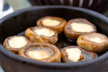 Close up mushrooms baked with cheese suluguni on ketsi. Georgian cousine.