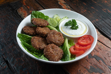 Falafel, vegan roasted chickpeas patties with garlic yogurt sauce isolated on rustic wooden table
