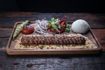 Turkish lula lamb or beef kebab with rice and vegetables isolated on rustic wooden table
