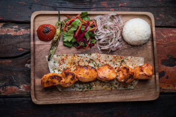 Turkish chicken sis kebab with rice and vegetables isolated on rustic wooden table