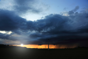 Fototapeta Pomarańczowo złoty zachód słońca nad polami, słupy elektryczne strugi deszczu. obraz