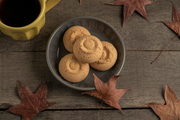 cup of coffee and cookies on a wooden table decorated with autumn leaves