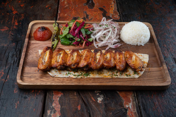 Turkish chicken wings kebab with rice and vegetables isolated on rustic wooden table
