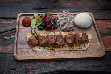 Turkish lamb sis kebab with rice and vegetables isolated on rustic wooden table