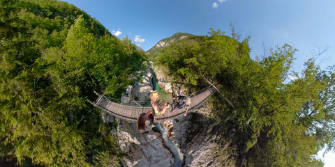 Obraz premium VR360: Active travelers and a puppy cross the hanging bridge over Soca river