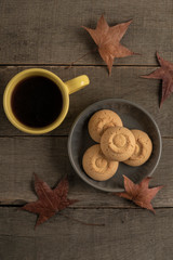 coffee and cookies on a wooden table decorated with autumn leaves