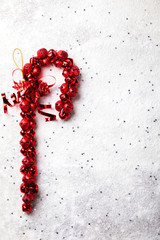 Traditional Christmas and New Year decor in the form of a red cane with a bell. Holiday decoration on a snowy background.Copy space