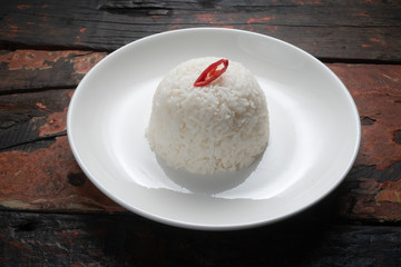 Jasmine steamed rice on the white plate isolated on rustic wooden kitchen table