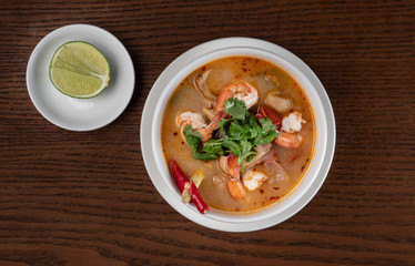 Top view Thai food Tom Yum soup with shrimps isolated on wooden table