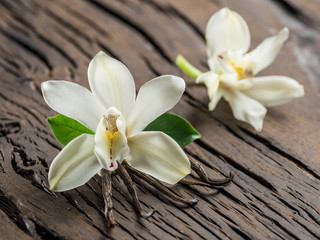 Dried vanilla sticks and vanilla orchid on wooden table.