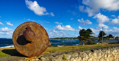 An old rusty cannon on the edge of coastline in Le Moule town in Guadeloupe, Grande-Terre island,...