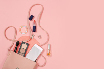 Fashion concept : Flat lay of brown leather woman bag open out with cosmetics, accessories and smartphone on pink background