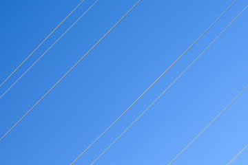 Electric wires against the blue sky.