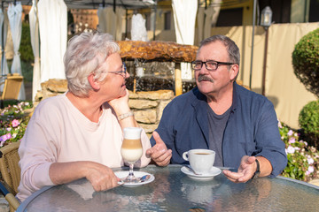 Loving Senior Couple Enjoying coffee and Talking At Outdoor Cafe. Happy retirement concept