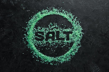 Green sea with the inscription SALT. On a black stone background. Spa treatments. Top view. Free space for your text.