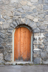 Fototapeta na wymiar wall with grey natural stones and wooden arched door