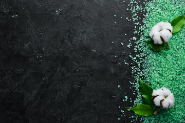 Green sea salt On a black stone background. Spa treatments. Top view. Free space for your text.