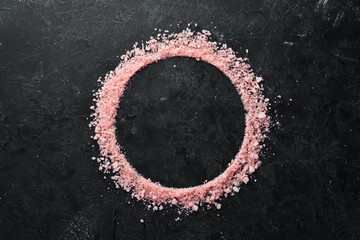 Obraz na płótnie Canvas Cosmetic pink sea salt. On a black stone background. Spa treatments. Top view. Free space for your text.