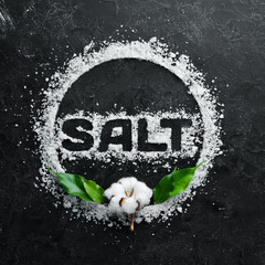 Sea salt with the inscription SALT. On a black stone background. Spa treatments. Top view. Free space for your text.