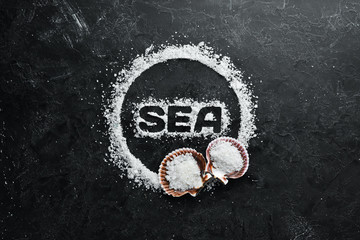 Sea salt with the inscription SEA. On a black stone background. Spa treatments. Top view. Free space for your text.