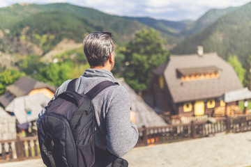 Man tourist with backpack arriving in mountain village.