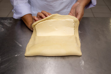 Chef hands making and folded raw puff pastry. Making puff pastry.   on a stainless steal table. First step, dough and the butter on the table.Close up. pastry chef. how to make.