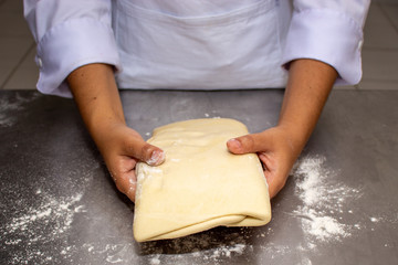 Chef hands making and folded raw puff pastry. Making puff pastry.   on a stainless steal table. First step, dough and the butter on the table.Close up. pastry chef. how to make.