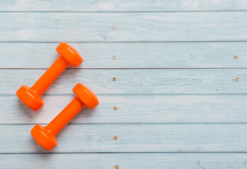 Fototapeta na wymiar Orange dumbbell on wooden table. Fitness healthy and sport concept