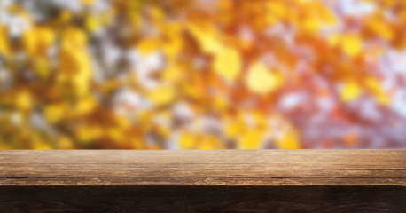 Naklejka na ściany i meble A wooden table top product display with a blurred background scene of tree foliage at sunset.