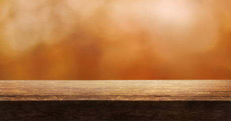 A wooden table top product display with a blurred background scene of blurred foliage at sunset.