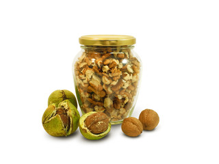 Walnut kernels in glass jar and whole fresh walnuts in green cracked peel and in shell, isolated on...