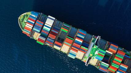Aerial top down photo of Container cargo Ship carrying load in truck-size colourful containers in...