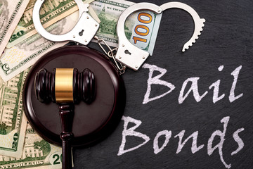 Bail bond system, bailing out of jail and innocent until proven guilty conceptual idea with judge wooden gavel, dollar banknotes and handcuffs with text Bail Bonds