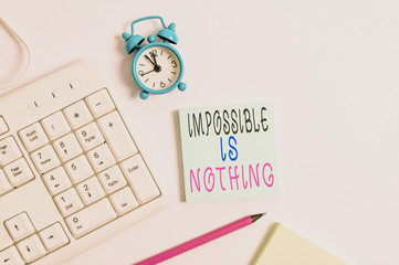Conceptual hand writing showing Impossible Is Nothing. Concept meaning Anything is Possible Believe the Realm of Possibility Keyboard with empty note paper and pencil white background