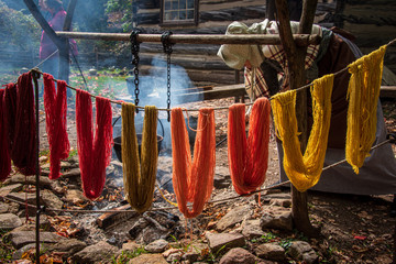 Fototapeta na wymiar pioneer woman dyeing and drying color yarn by an open fire