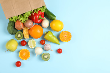 Naklejka na ściany i meble Paper bag, vegetables and fruits on blue background, space for text