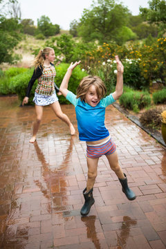 5 year old boy and his 13 year old sister dancing in the rain.