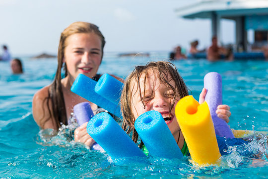 siblings playing in pool with floaties