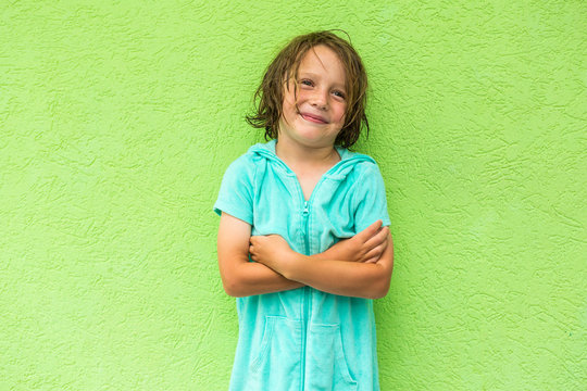 smiling 5 year old boy posing in front of green wall