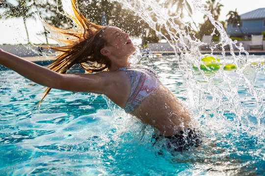 13 year old girl tossing her wet hair bak, in pool