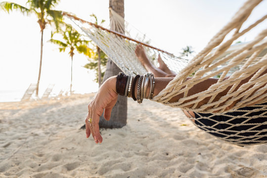 close up of woman's arm and bracelets, resting  in hammock