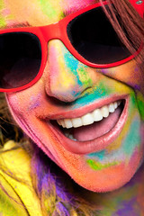 Excited woman face covered in rainbow colored powder